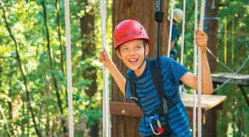 A boy smiling and looking up on a ropes course