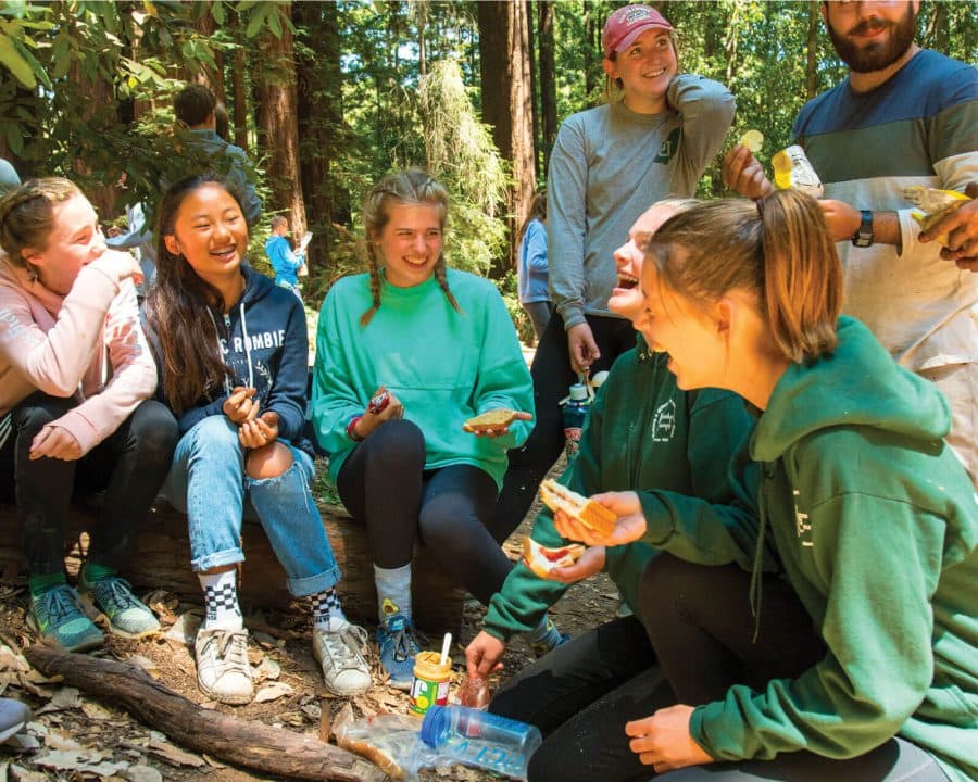 Campers eating PB and J's and laughing outdoors