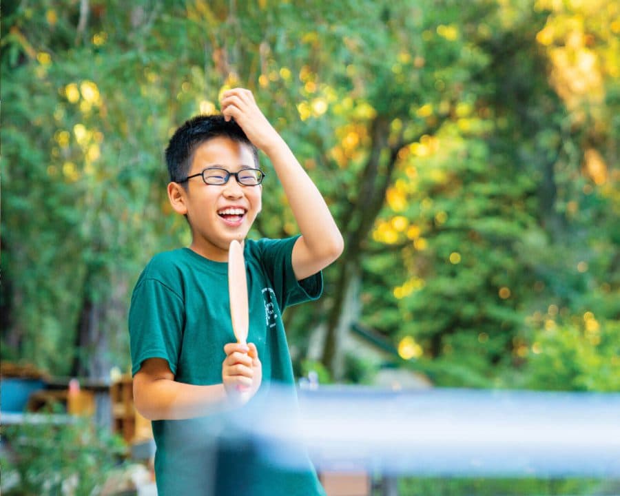 A boy laughing while playing ping pong
