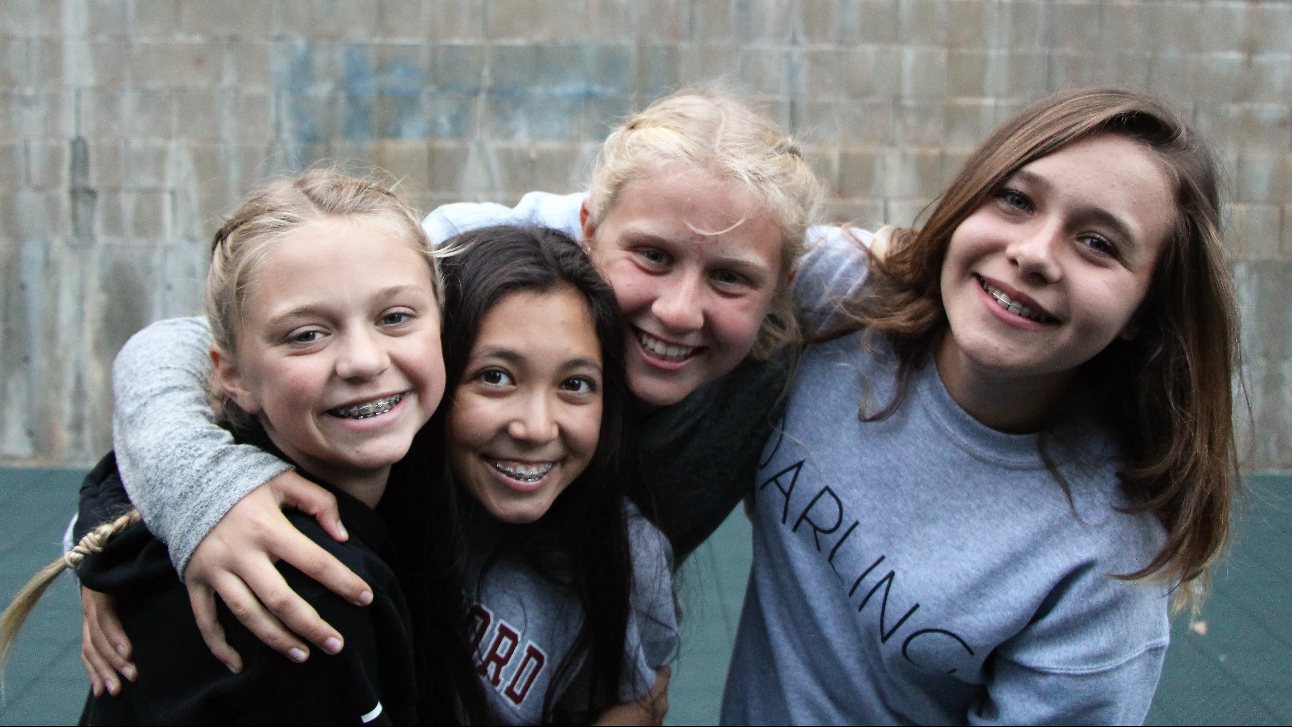 Four girls happily holding eachother and smiling