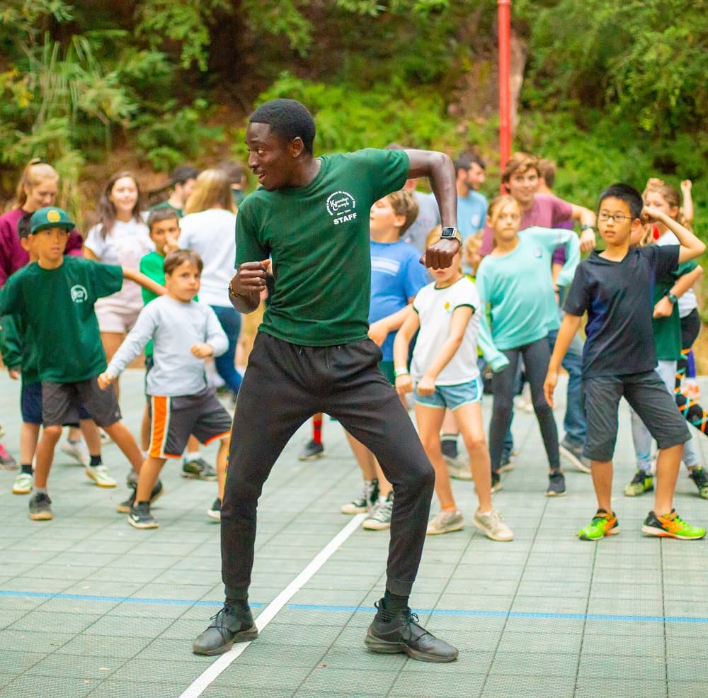 A counselor teaching a dance to campers