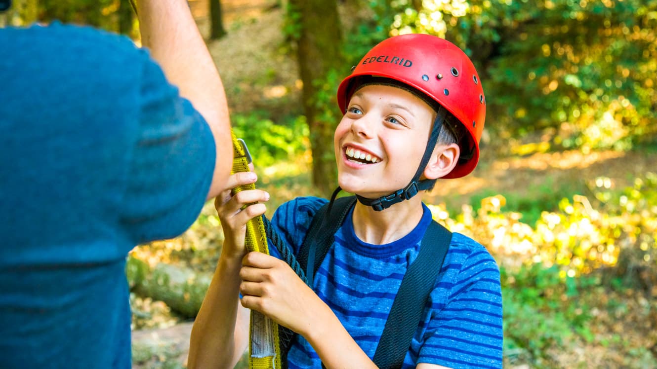 Smiling boy wearing red helmet at summer camp