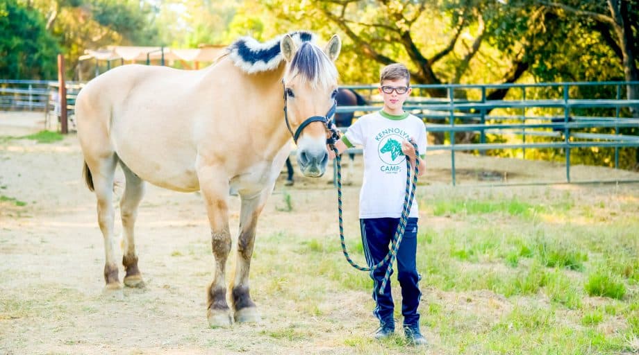 Boy walks pony at summer camp