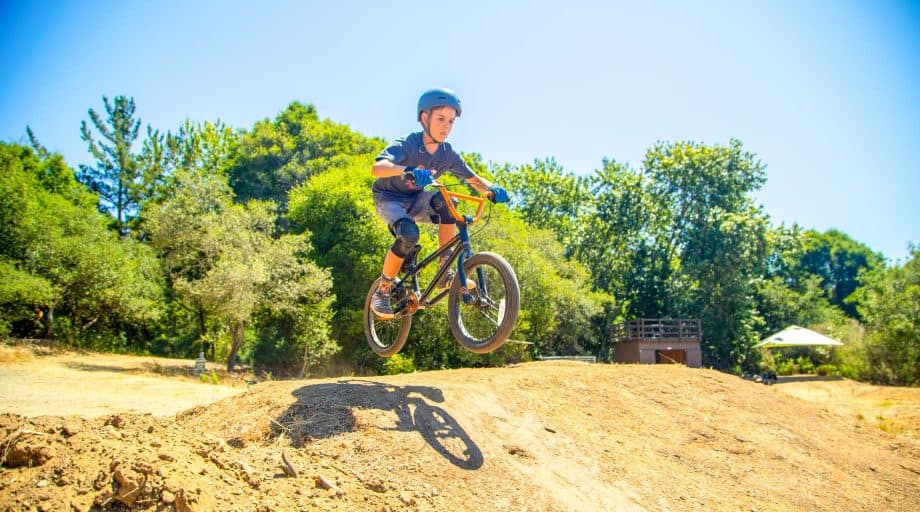 Boy jumps BMX bike at summer camp