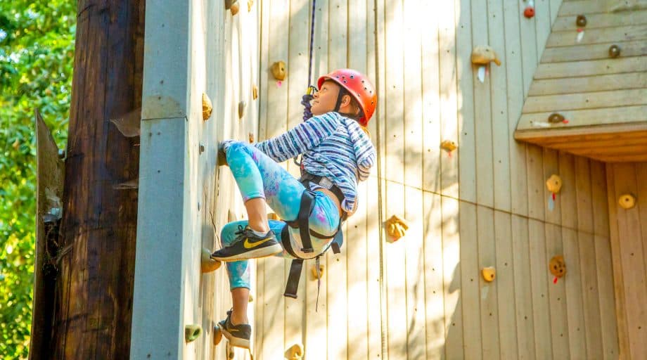 Side view of camper climbing rock wall