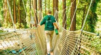 A camper walks accross a rope bridge