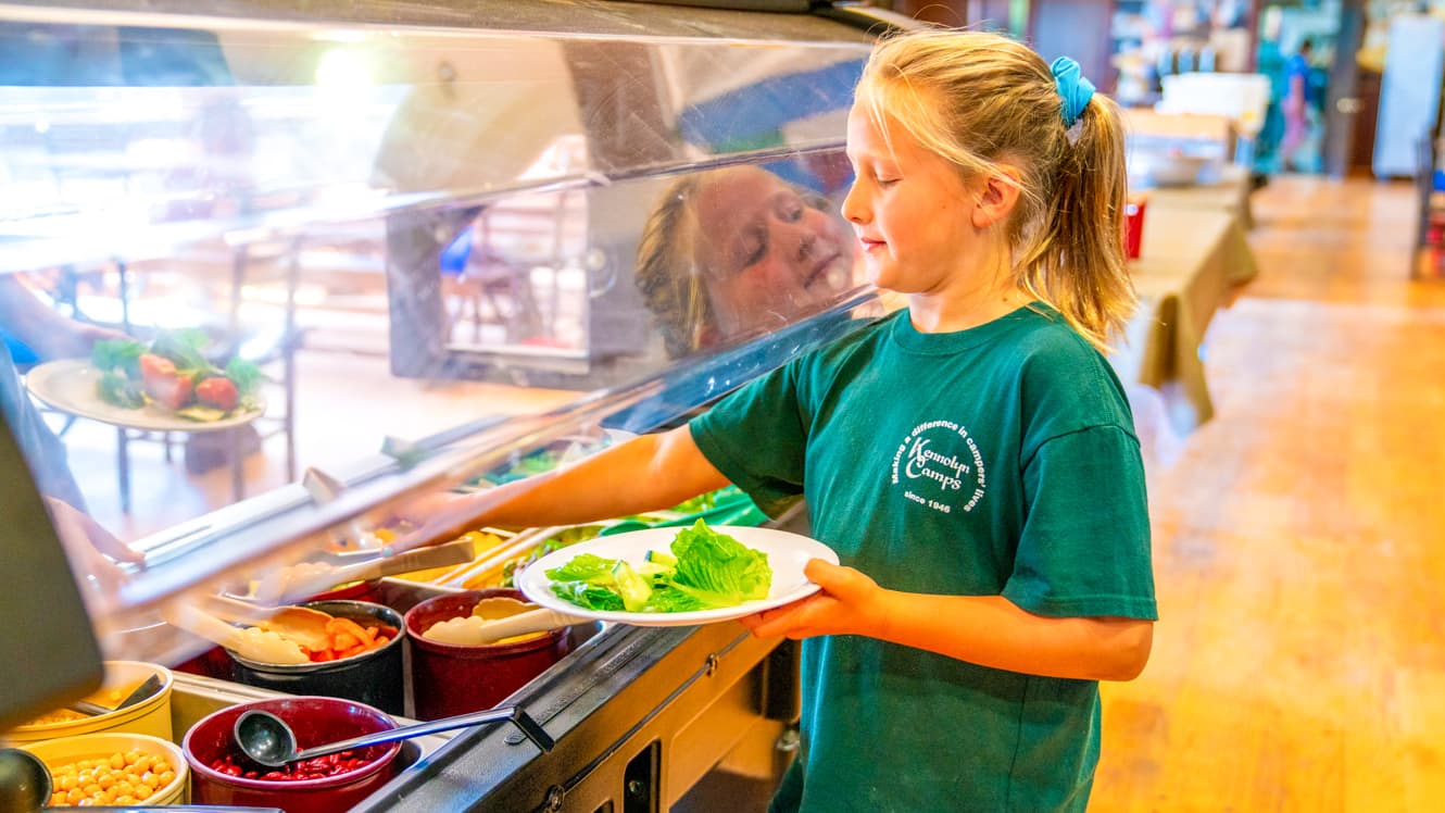 Girl gets lettuce from summer camp salad bar