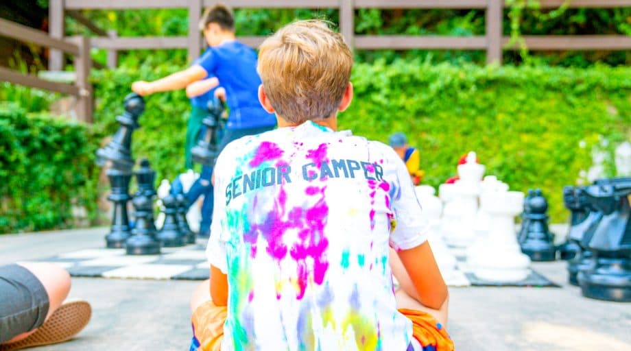 Camper sits near giant chess board