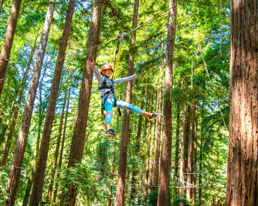Camper splays arms and legs while ziplining at summer camp