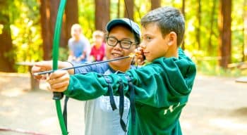 Two campers aim bow at summer camp