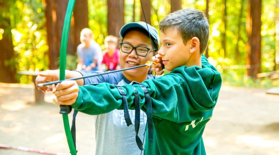 Two campers aim bow at summer camp