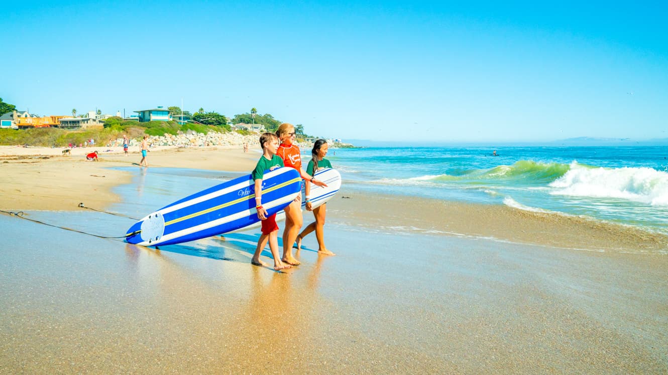Campers walk down beach with surfboard
