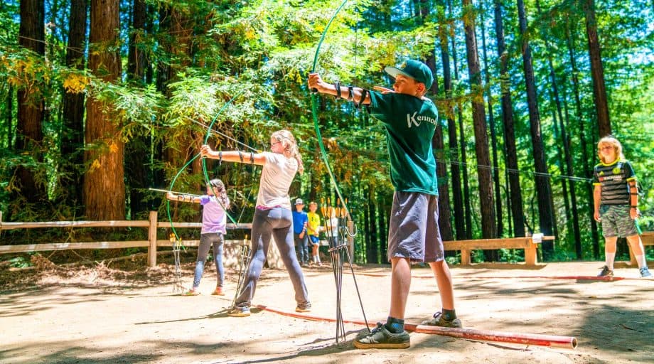 Campers draw bows during archery