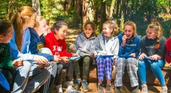 Girls sitting on logs eating lunch