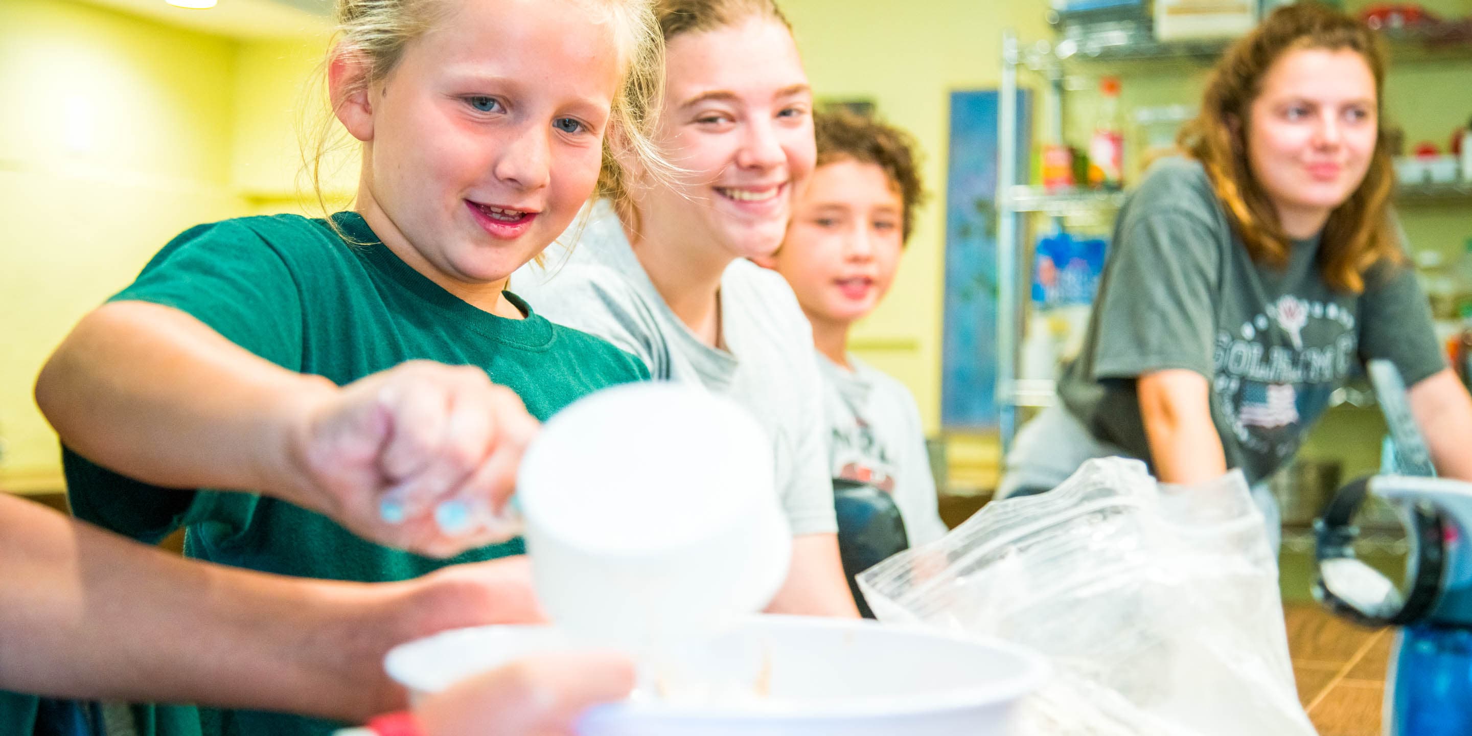 Campers scoop flour while baking at summer camp