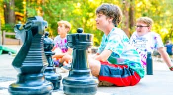 Campers listening to someone before playing giant chess