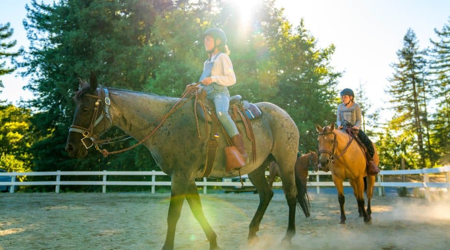 Campers ride horse in summer camp ring