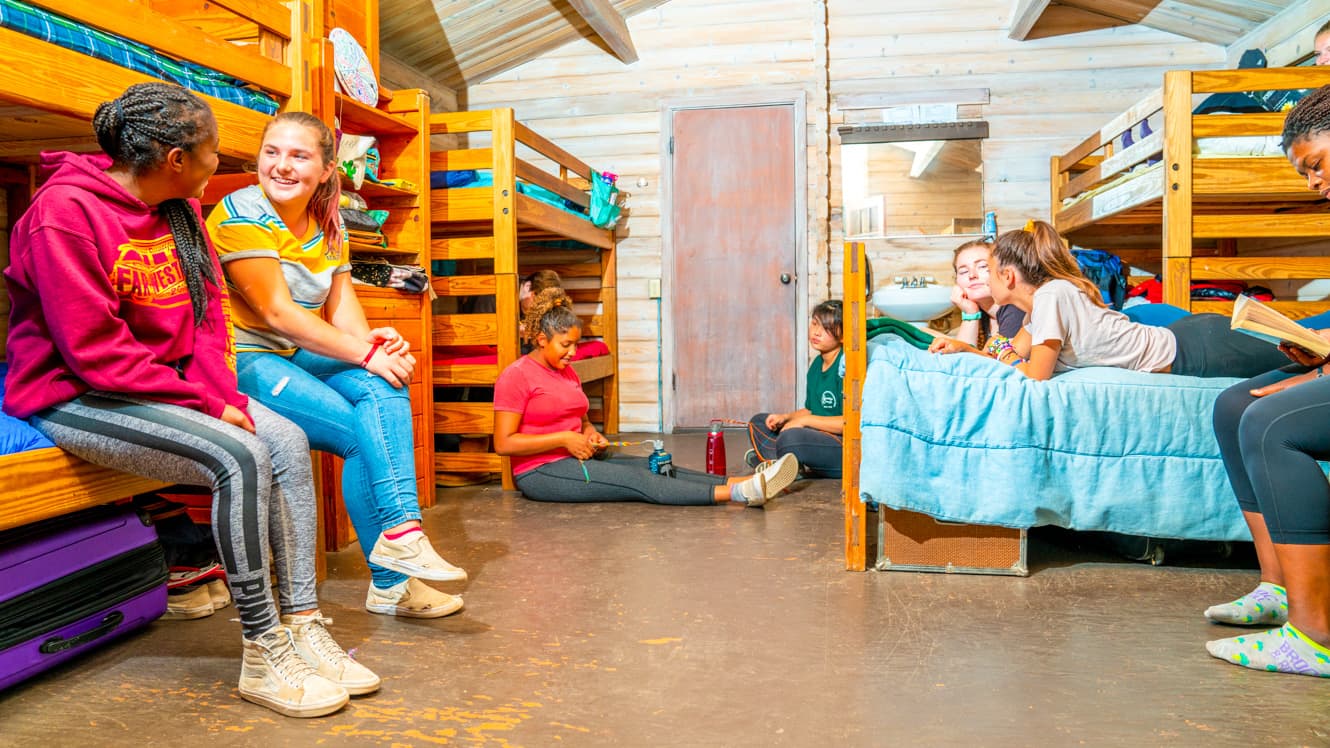 Girls lounge on bunks in camp cabin