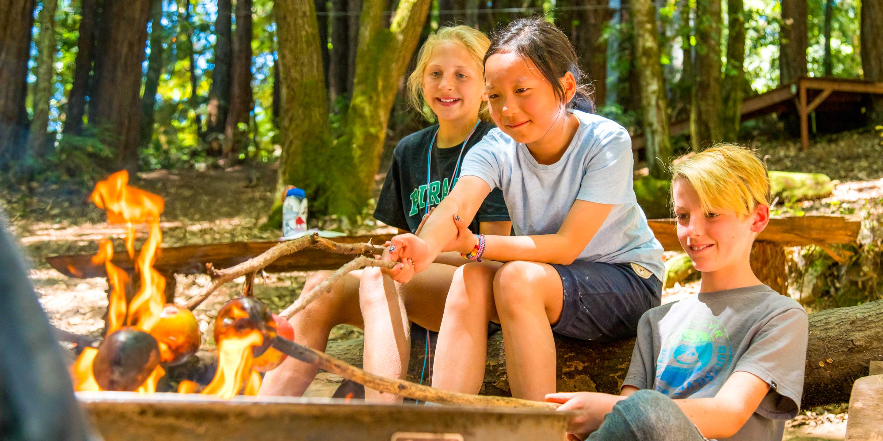 Campers roast apples over outdoor fire