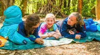 Three girls talking in sleeping bags outdoors