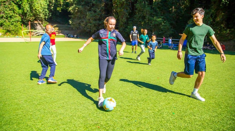 Group of campers play soccer at summer camp