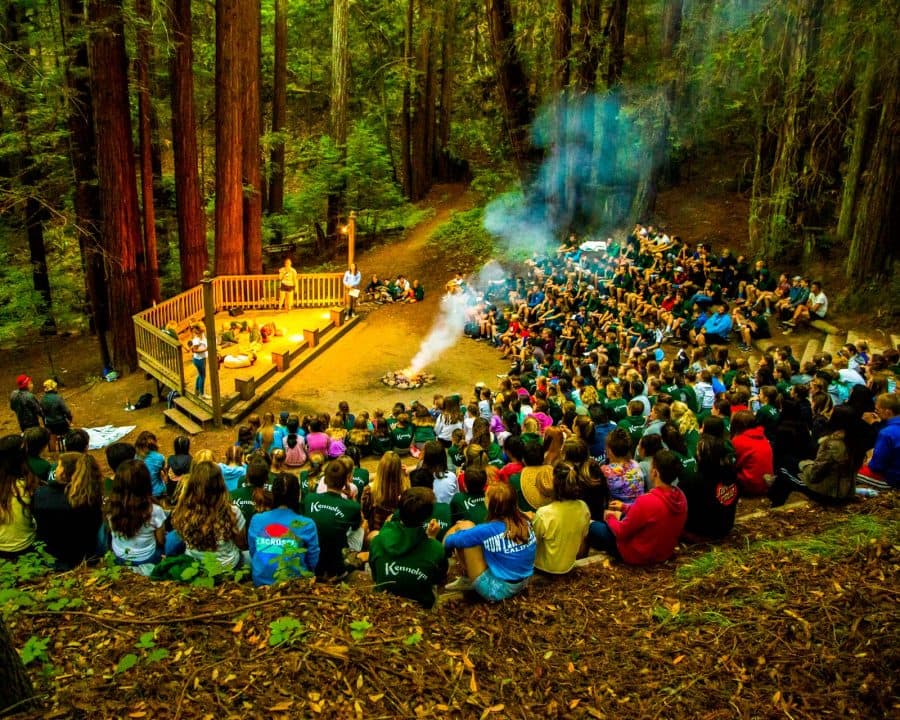 Campers gather around campfire among the redwoods
