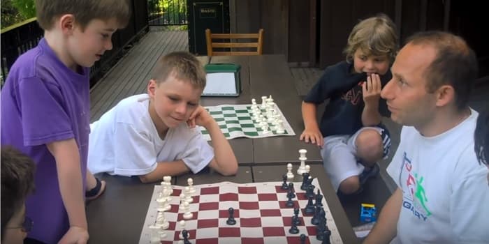 Kids look on as a counselor teaches them about chess