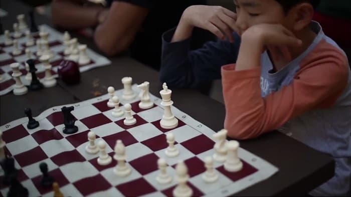 A boy looks over a chess board