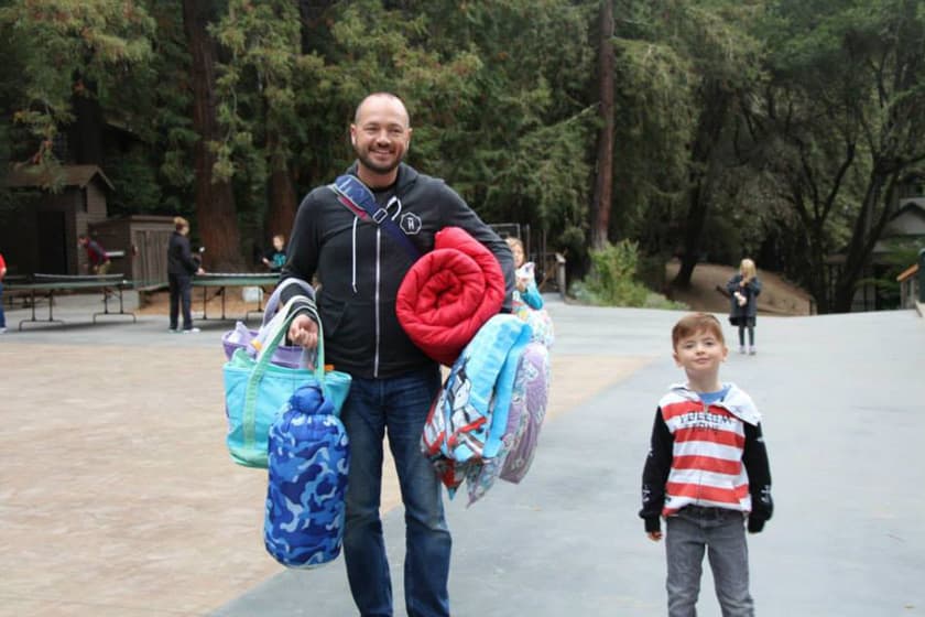 A father holding luggage with his young son next to him