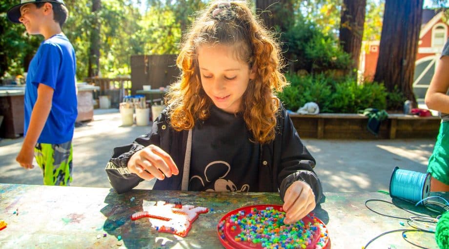 Girl makes bead pattern at summer camp