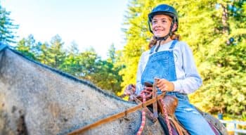 A girl on a horse in overalls