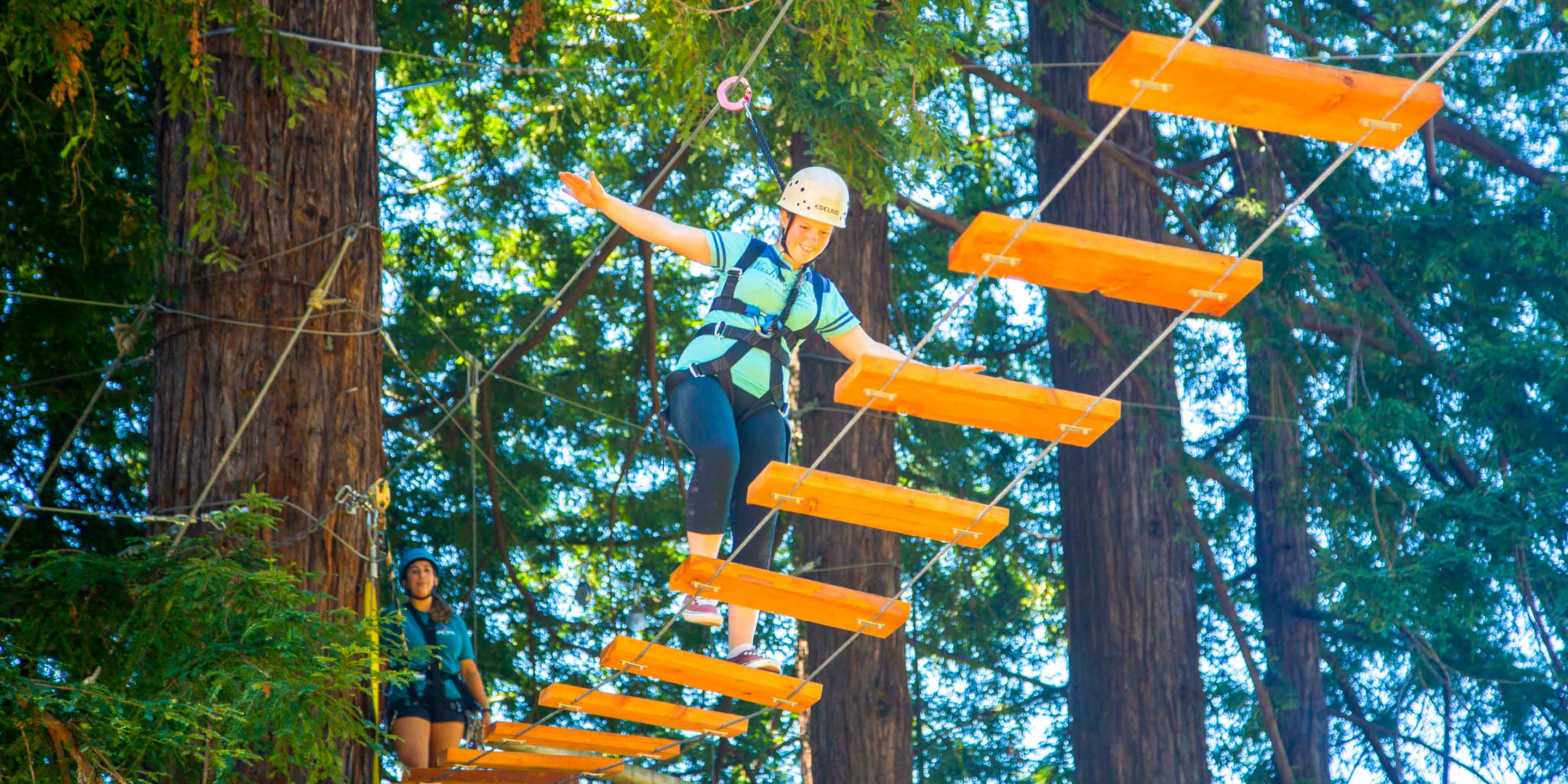 Camper does plank walk on ropes course