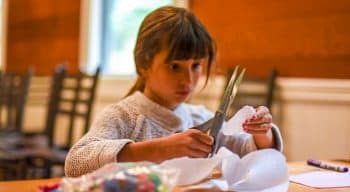 Girl uses scissor while doing fashion design at summer camp