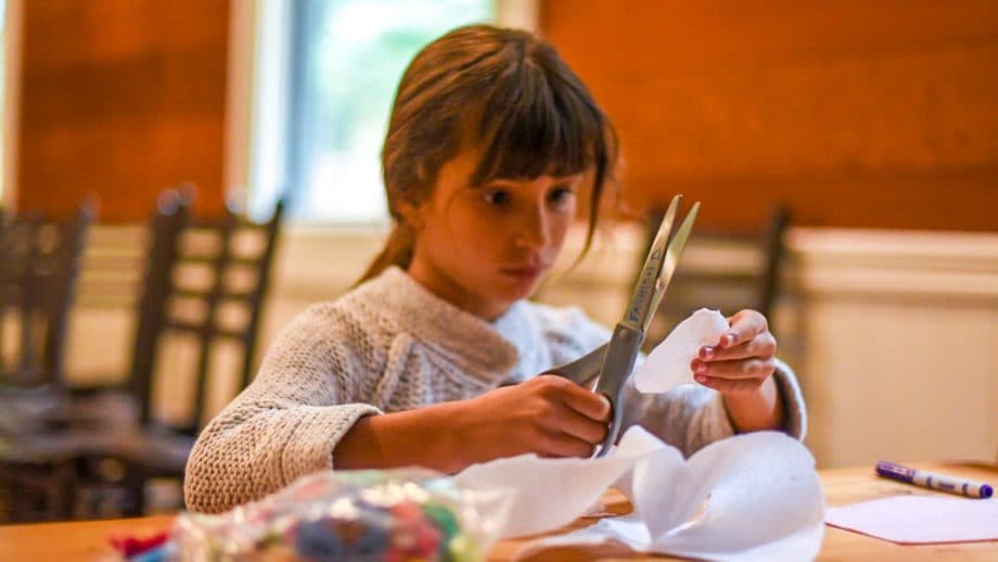 Girl uses scissor while doing fashion design at summer camp