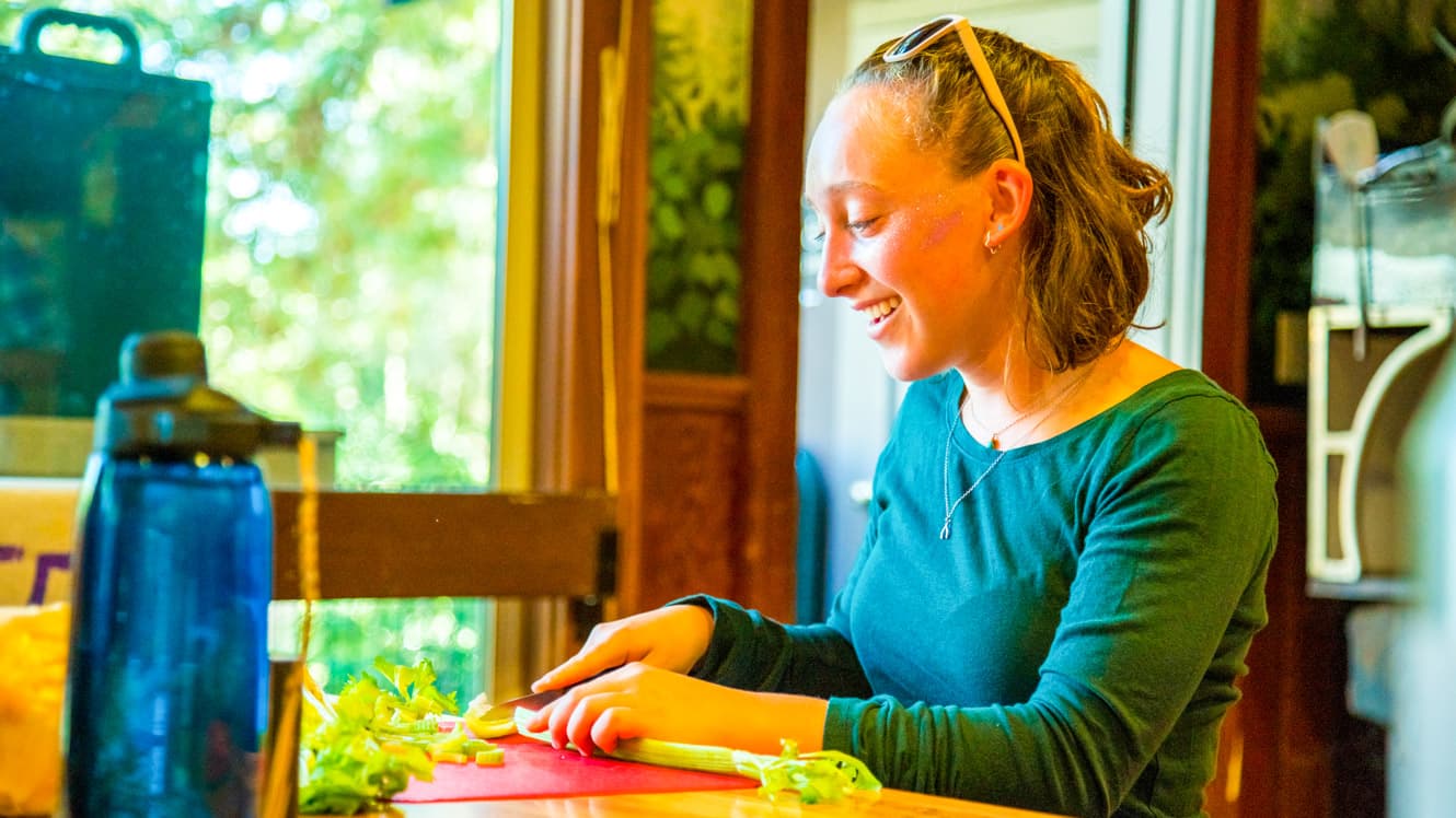 Girl slices celery during summer camp culinary arts