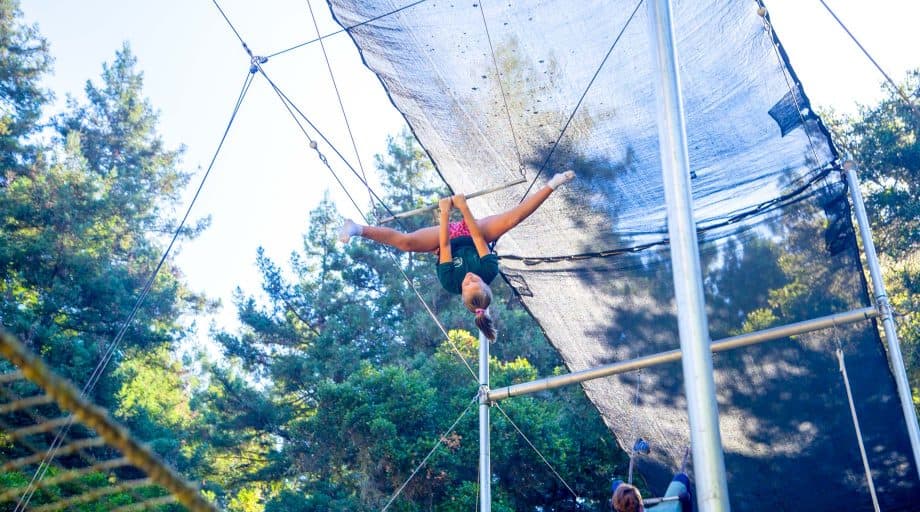 Girl swings on trapeze at summer camp