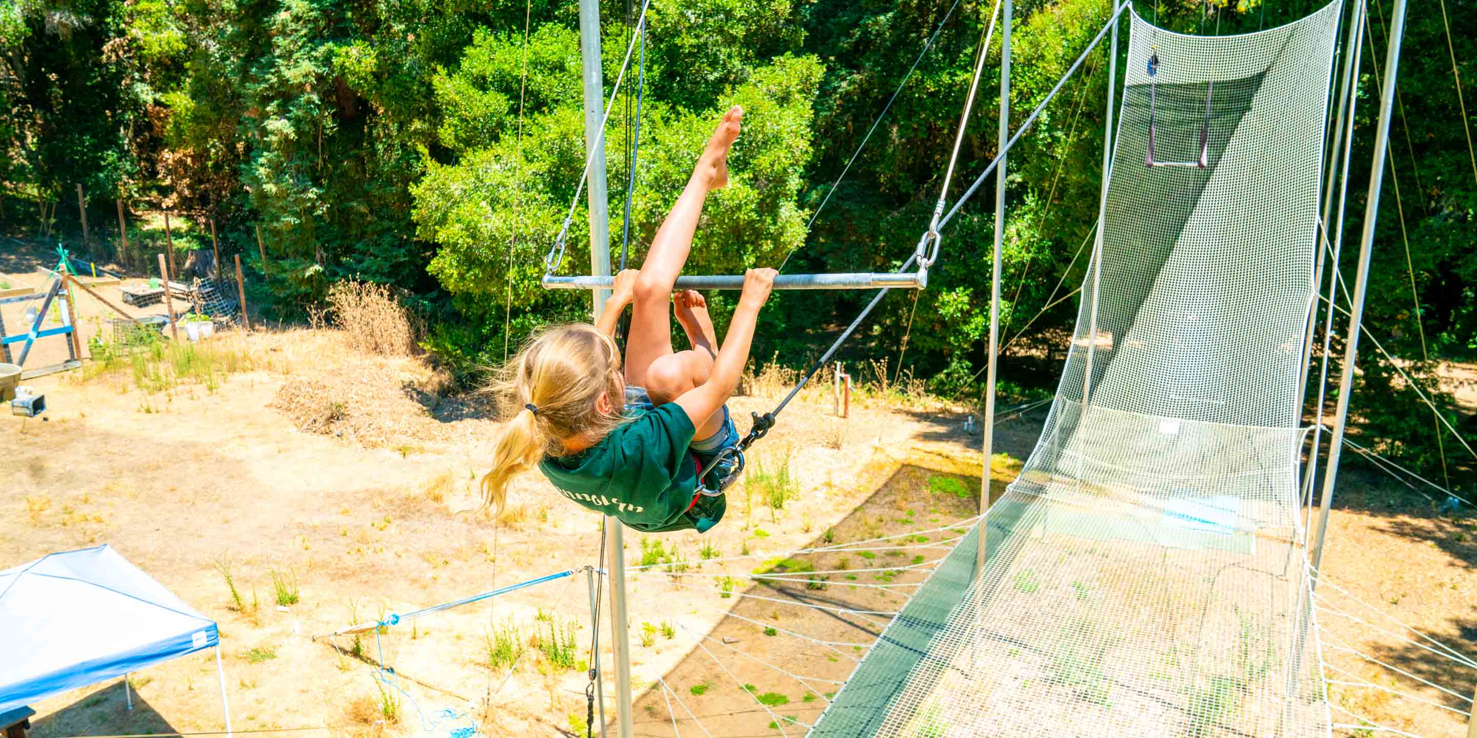 Girl swings legs over trapeze while swinging