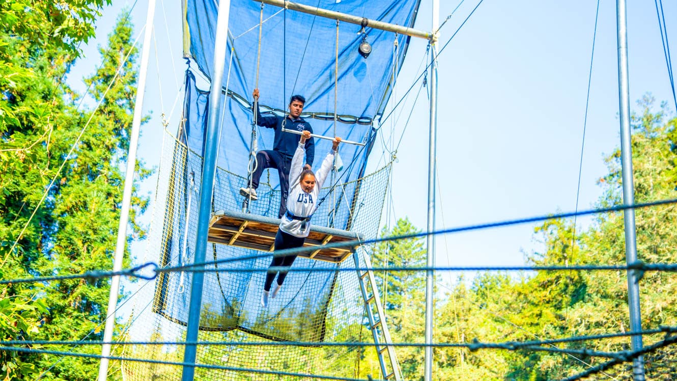 Girl swings on trapeze at summer camp
