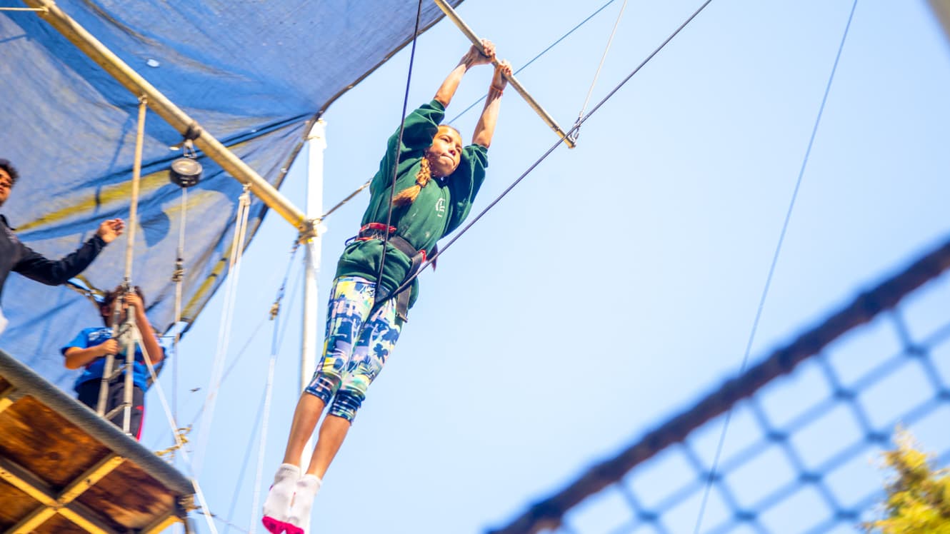 Girl swings on trapeze at summer camp