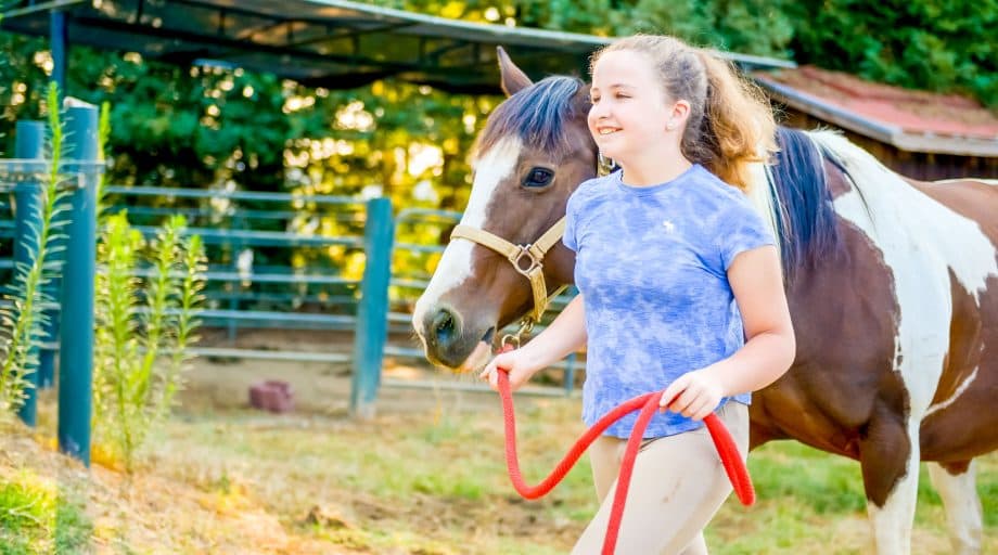 Girl walks horse at summer camp