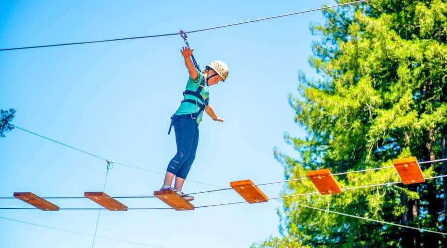 Girl walks across planks of ropes course
