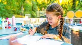 A girl with braids writing a letter