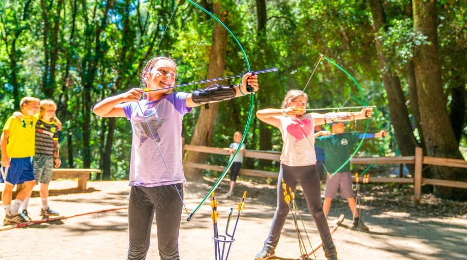 Girls do archery at summer camp