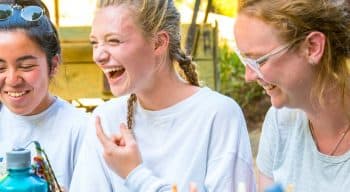 Three girls laughing while doing crafts