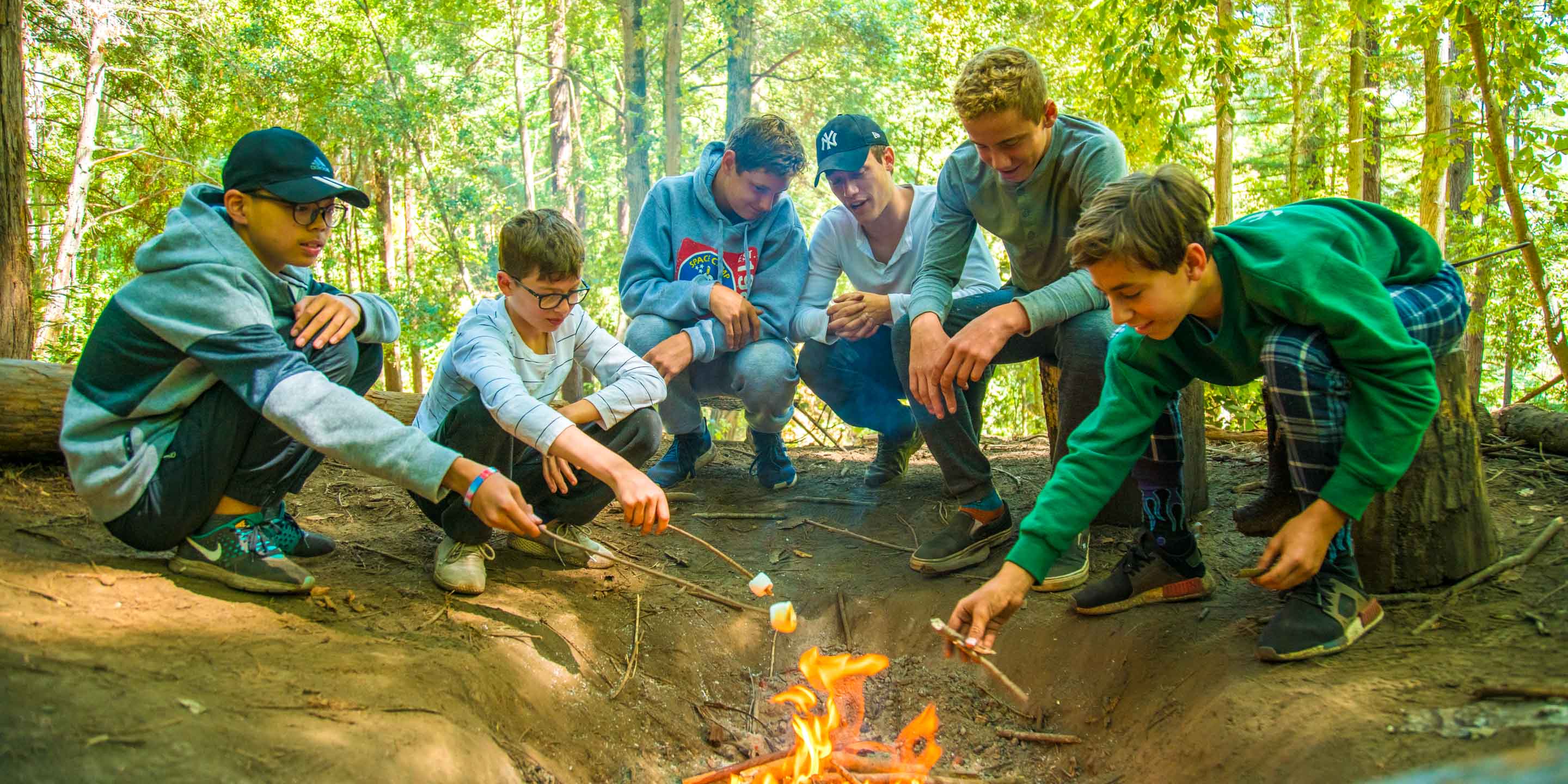 Group of campers roast marshmallows over fire