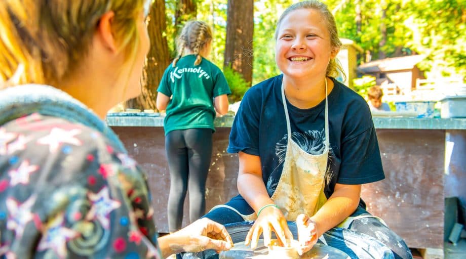 Girl laughs while making wheel pottery