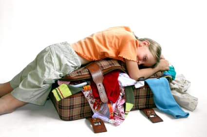 A girl laying on her overfilled luggage