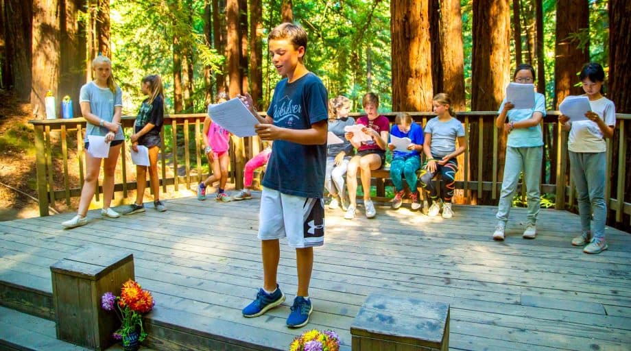 Boy rehearses play with campers behind him