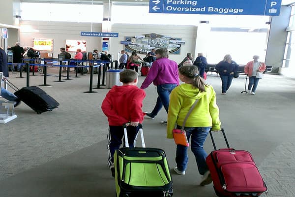 Two kids walking through an airport with luggage