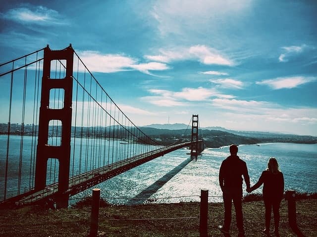 A couple holding hands looking out over the golden gate bridge